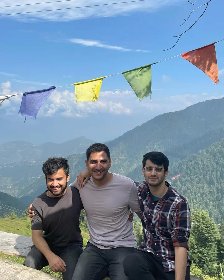 Priyansh with two friends on a hillside under prayer flags